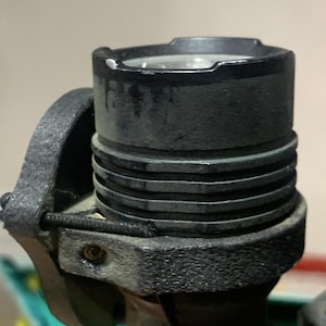 Puede incluir: Una linterna negra con un agarre de goma negra texturizado. La linterna tiene un cuerpo de metal negro con un anillo plateado alrededor de la lente.