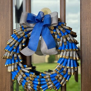 May include: A blue and gray wreath made of shotgun shells with a blue and gray bow.