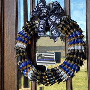 May include: A wreath made of shotgun shells with a blue and black ribbon with the text "Back the Blue" and a thin blue line American flag.