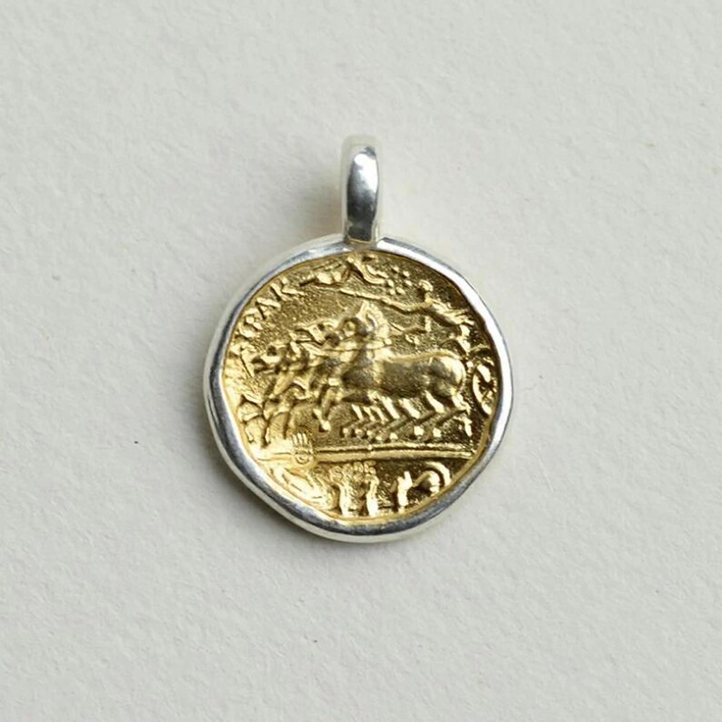 May include: A gold-plated silver pendant featuring a Roman coin design with a chariot and horses. The pendant is round and has a silver bail.