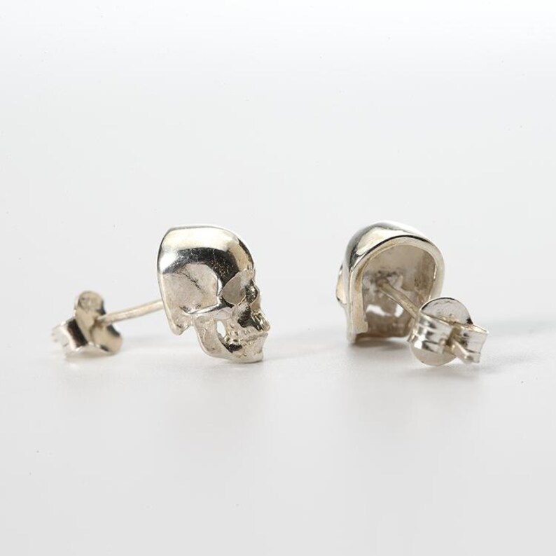 Pu&ograve; includere: Un paio di orecchini a lobo in argento a forma di teschio. Gli orecchini sono in metallo e hanno un design di teschio dettagliato.