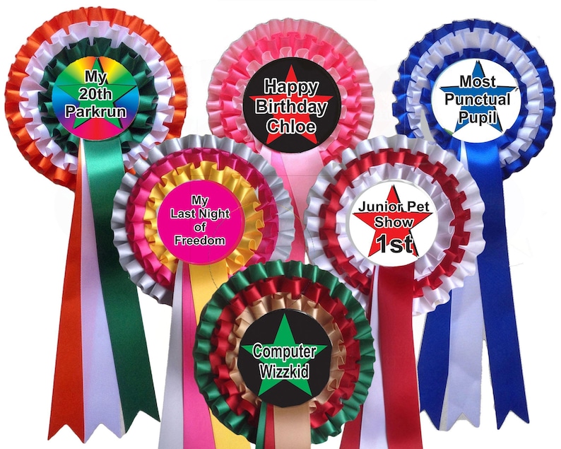 A selection of colourful rosettes  in a wide range of different colours. Each rosette has a customised centre and three layers of coloured pleated ribbon. These rosettes are  from a range of personalised rosettes that can be personalised for any party, occasion, celebration, such as  a hen night, birthday, stag night, event, compertiton, award