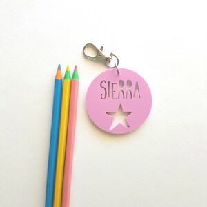 May include: Pink plastic keychain with a star cut-out and the name "SIERRA" in white lettering.
