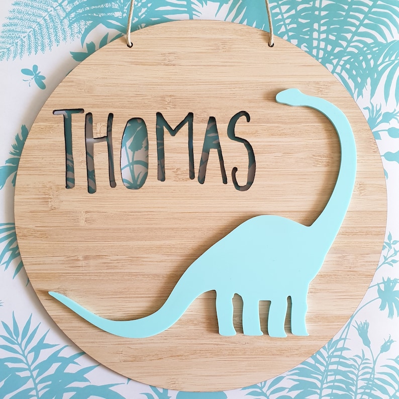 a bamboo name plaque with a colourful dinosaur.  it is personalised with a name