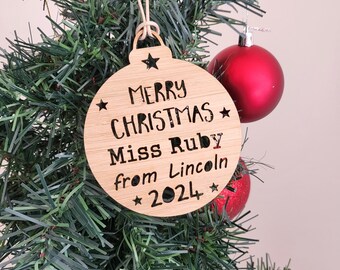 May include: A wooden Christmas ornament with the text "Merry Christmas* Miss Ruby from Lincoln *2024*" hanging on a green Christmas tree.