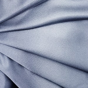 Swatch of mid weight dusky medium denim blue 100% polyester crepe back satin fabric for bag.