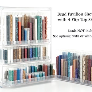 May include: Clear plastic bead storage organizer with four flip-top shelves. The organizer is filled with small containers of colorful beads. "Bead Pavilion Showcase with 4 Flip Top Shelves" and "Beads NOT included" are written on the organizer. "See options; with or without containers" is also written on the organizer.