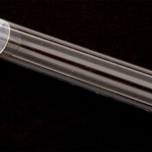 May include: A clear plastic tube with a white plastic cap on one end. The tube is about 10 inches long and 1 inch in diameter.
