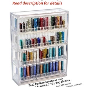 May include: Clear plastic bead storage organizer with four shelves. The organizer has two round shelves and two flip-top shelves. The shelves are filled with small glass vials of colorful beads. "Bead Pavilion Showcase with 2 Round & 2 Flip Top Shelves. Beads NOT included. See options; with or without containers." is printed on the bottom of the organizer.