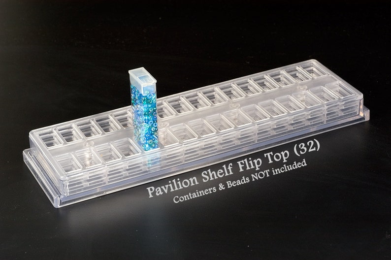 May include: A clear plastic bead storage organizer with 32 compartments. The organizer has a flip top and is labeled "Pavilion Shelf Flip Top (32)".  Containers & Beads NOT included.