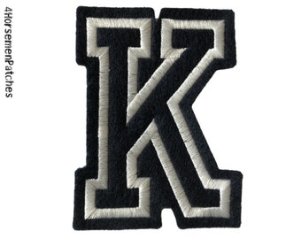 以下が含まれることがあります： 白い縁取りのある黒い刺繍文字「K」のパッチ。パッチは質感のある外観で、白い背景に配置されています。「4HorsemenPatches」の文字が左側にあります。