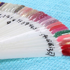 May include: A nail polish color chart with a variety of colors, including red, green, gold, and silver. The chart is labeled with numbers from 1 to 55.
