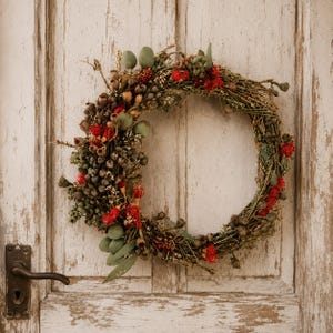 Handmade Australian native dried flower wreath featuring eucalyptus gum nuts, bottlebrush, preserved foliage and rustic twigs, displayed on a weathered white timber door with vintage hardware. An everlasting wreath perfect for front door décor, farmhouse styling, Christmas or Australian home décor