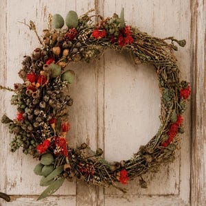 Handmade Australian native dried flower wreath featuring eucalyptus gum nuts, bottlebrush, preserved foliage and rustic twigs, displayed on a weathered white timber door with vintage hardware. An everlasting wreath perfect for front door décor, farmhouse styling, Christmas or Australian home décor