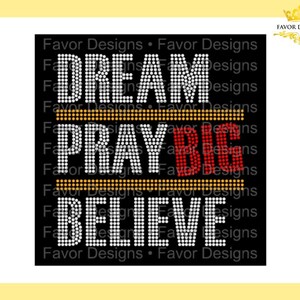 May include: Black background with white rhinestone lettering that reads "Dream Pray Big Believe". The word "Big" is in red rhinestones.