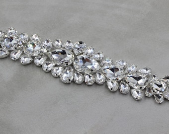 May include: A silver trim rhinestone embellishment with clear teardrop-shaped crystals.