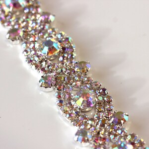 May include: A silver-toned, iridescent rhinestone trim with a repeating pattern of small and large rhinestones.