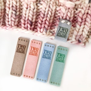May include: Five leather labels with the text "TWO LITTLE RAINBOWS" in different colours: brown, pink, blue, light blue, and green.