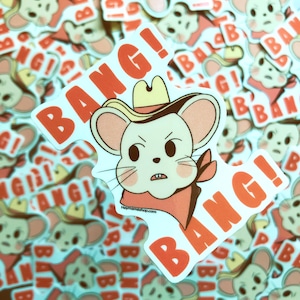 May include: A white sticker with a cartoon mouse wearing a cowboy hat and bandana. The mouse has a grumpy expression and the sticker says "Bang!" in red letters.