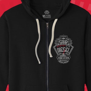 Puede incluir: Sudadera negra con cremallera y capucha con un diseño gráfico blanco que incluye el texto "Sour Diesel" en rojo. El gráfico también incluye el texto "Homegrown" y una imagen estilizada de una hoja de cannabis.