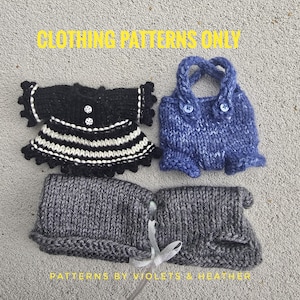 May include: Four small, hand-knitted clothing items in black, blue, and gray. One is a black dress with white stripes and trim. Another is a blue top with straps and buttons. The text "CLOTHING PATTERNS ONLY" and "PATTERNS BY VIOLETS & HEATHER" are visible.