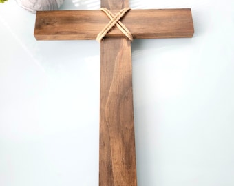 May include: A wooden cross with a rustic brown finish. The cross is tied together with twine.