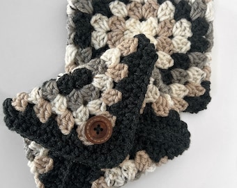 Può includere: Set fatto a mano composto da scaldacollo e scaldapolsi all'uncinetto. Il set presenta un motivo a granny square nei toni del nero, grigio, crema e beige. Lo scaldapolsi ha una chiusura con bottone in legno. Un set accogliente per l'inverno.
