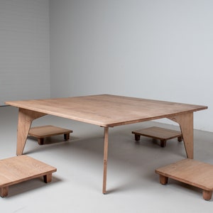May include: A square wooden table with four matching wooden stools. The table and stools are made of light brown wood and have a simple, modern design.