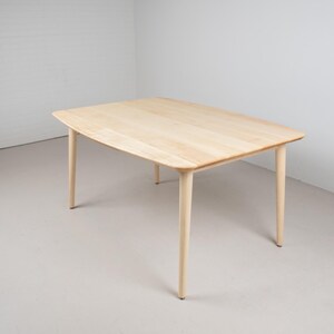 May include: A light wood dining table with a rectangular top and four legs. The table is made of a light wood and has a natural finish.