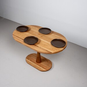 small oval kitchen table made of oak on pedestal base