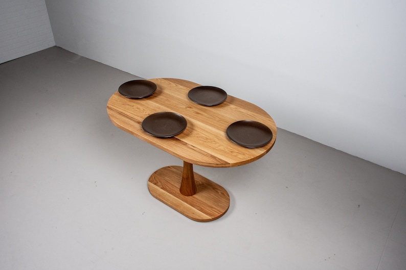 small oval kitchen table made of oak on pedestal base