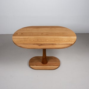 small oval kitchen table made of oak on pedestal base