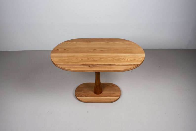 small oval kitchen table made of oak on pedestal base
