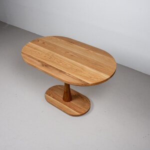 small oval kitchen table made of oak on pedestal base