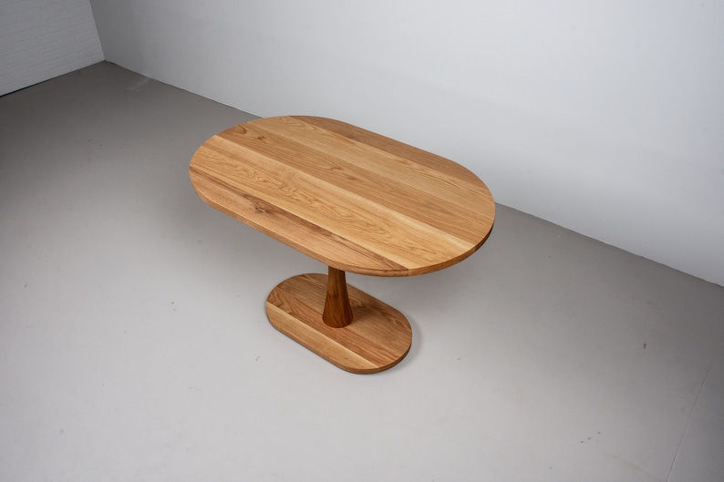 small oval kitchen table made of oak on pedestal base