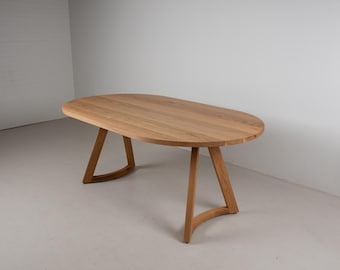 May include: Oval wooden dining table with a light brown finish. The table has a smooth surface and is supported by four angled legs with curved bases. The table is approximately 72 inches long and 40 inches wide.