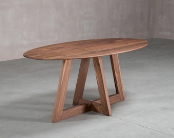 May include: An oval dining table crafted from dark brown wood with a visible grain pattern. The table features a smooth, flat top supported by a structural base consisting of four angled legs that meet in a central cross-braced configuration.