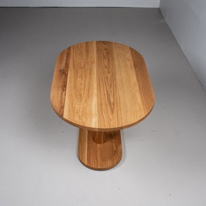 small oval kitchen table made of oak on pedestal base