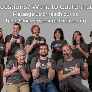 May include: A group of eight people wearing grey t-shirts with the logo "Loewen Design Studios" printed on them. They are all giving a thumbs up. The text "Questions? Want to Customize? Message us or reach out at hello@loewendesignstudios.com" is displayed at the top of the image.