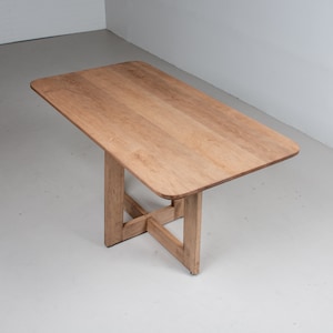 May include: A light wood table with a rectangular top and a simple, cross-shaped base.