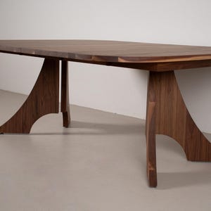 May include: A large, solid wood dining table with a dark brown finish. The table features a rectangular top and unique, curved legs. The table's dimensions are approximately 72 inches long, 36 inches wide, and 30 inches high.