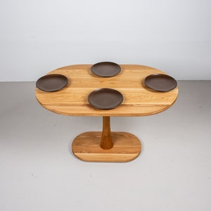 small oval kitchen table made of oak on pedestal base