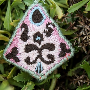 May include: A pink, brown, and blue embroidered triangle with a floral pattern.