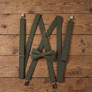 Può includere: Set di bretelle e papillon verde oliva su sfondo in legno. Le bretelle hanno clip in metallo color argento. Il papillon è pre-annodato. Adatto per eventi formali o per aggiungere un tocco di stile a un outfit.