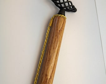 May include: A wooden walking stick with a black metal handle and a gold cord wrapped around the shaft.