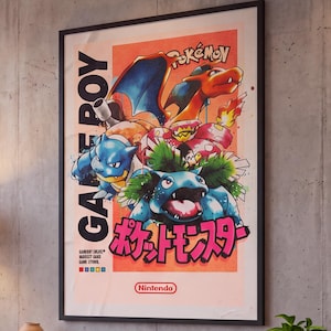 May include: A framed vertical poster featuring a Game Boy graphic with illustrations of Charizard, Blastoise, and Venusaur. The artwork includes the text Pokémon, Nintendo, and Japanese characters in pink, set against a light orange background.