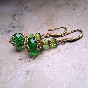 May include: Green and gold dangle earrings with a large green faceted bead and smaller green beads on a gold wire.