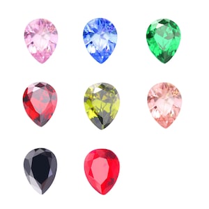 May include: Nine pear-shaped gemstones in various colors, including pink, blue, green, red, black, and brown. The gemstones are arranged in a grid pattern on a white background.