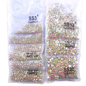 May include: Assortment of clear iridescent rhinestones in various sizes, packaged in individual clear plastic bags. Each bag contains 1440 pieces and is labeled with the size, "SS3", "SS12", "SS16", and "SS20".