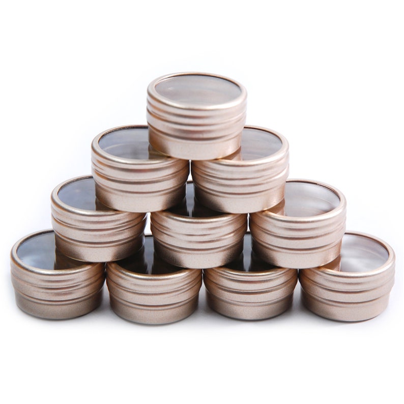 May include: A stack of ten gold metal containers with clear lids. The containers are arranged in a pyramid shape.